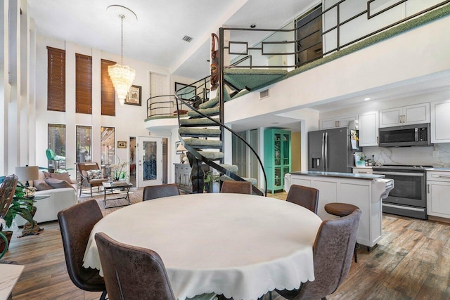 dining space featuring wood-type flooring and a high ceiling