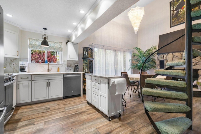 kitchen featuring appliances with stainless steel finishes, sink, backsplash, ornamental molding, and light hardwood / wood-style flooring