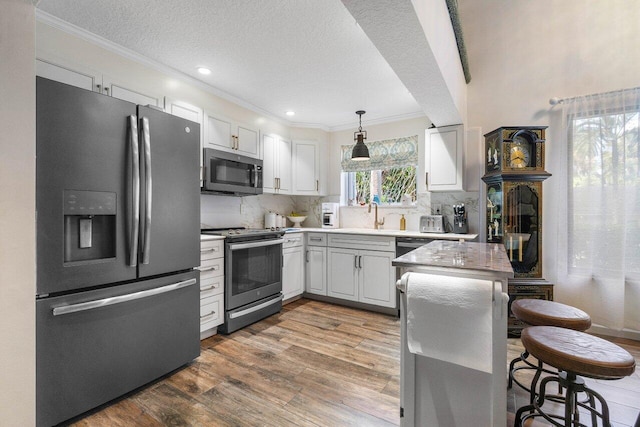 kitchen with pendant lighting, dark wood-type flooring, white cabinetry, backsplash, and appliances with stainless steel finishes