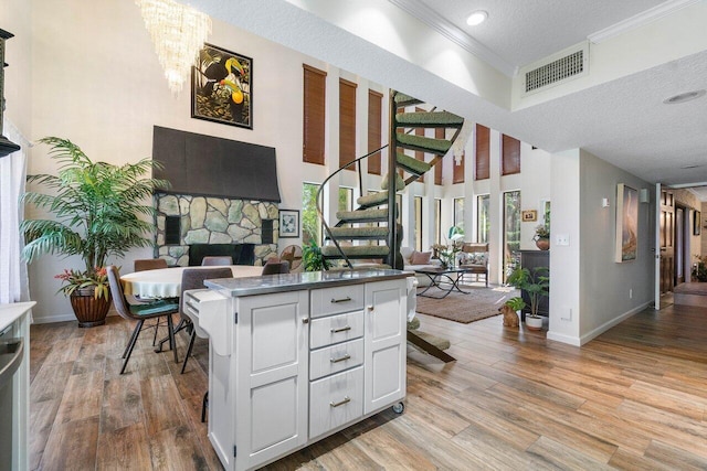 kitchen with a stone fireplace, light hardwood / wood-style flooring, white cabinets, and a textured ceiling