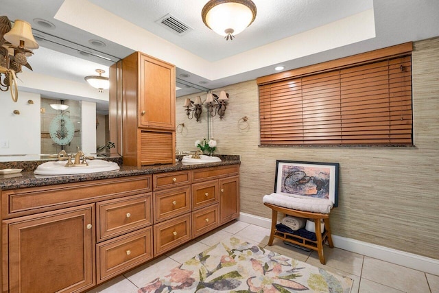 bathroom featuring dual bowl vanity, a textured ceiling, tile floors, and a raised ceiling