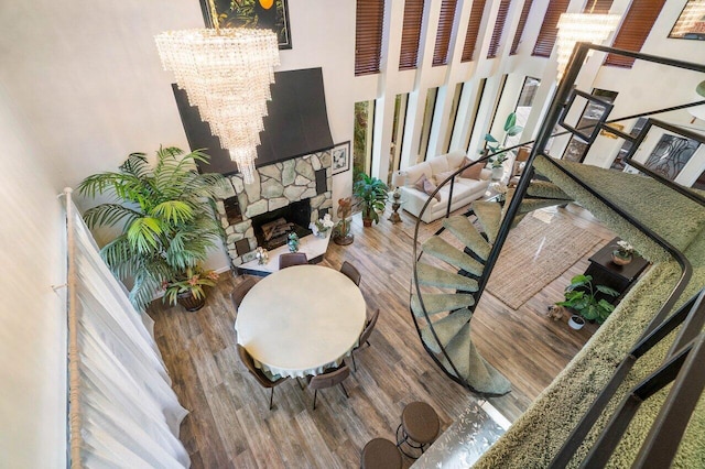 living room featuring hardwood / wood-style floors, a high ceiling, a fireplace, and an inviting chandelier