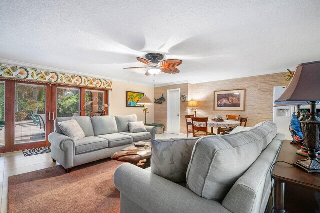 tiled living room featuring french doors, crown molding, ceiling fan, and a textured ceiling