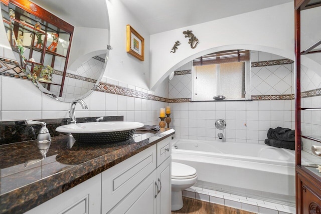 bathroom featuring tile walls, oversized vanity, a tub, toilet, and hardwood / wood-style flooring