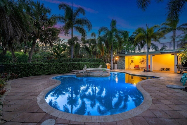 pool at dusk with a patio and an in ground hot tub