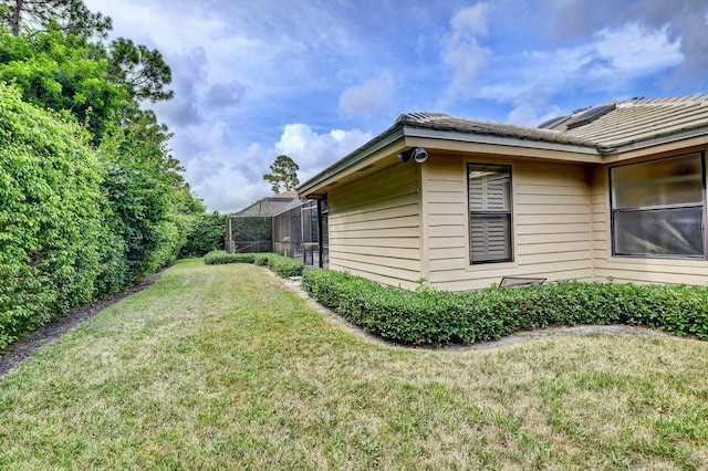 view of home's exterior featuring glass enclosure and a lawn