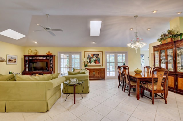 tiled dining space featuring lofted ceiling with skylight, french doors, a healthy amount of sunlight, and ceiling fan with notable chandelier