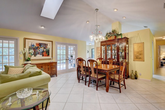 tiled dining area featuring french doors, vaulted ceiling with skylight, and a chandelier