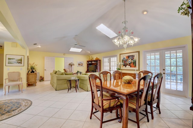 tiled dining room with ceiling fan with notable chandelier, french doors, and vaulted ceiling with skylight