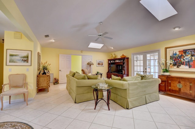 tiled living room with french doors, ceiling fan, and lofted ceiling with skylight