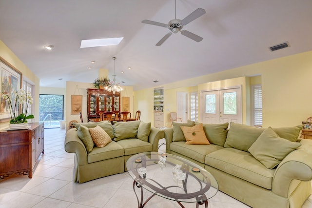 tiled living room with ceiling fan and vaulted ceiling with skylight