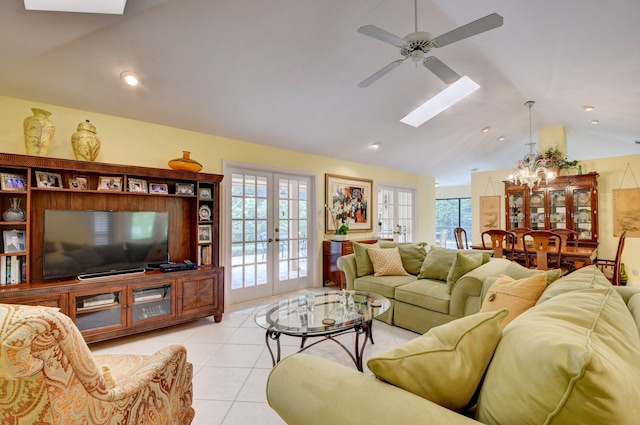 tiled living room with lofted ceiling with skylight, french doors, a healthy amount of sunlight, and ceiling fan with notable chandelier