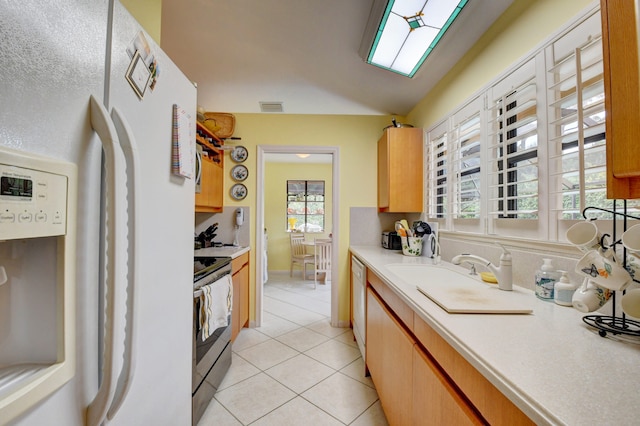 kitchen featuring stainless steel electric range, sink, dishwasher, light tile flooring, and refrigerator