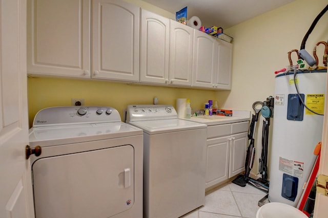 clothes washing area with water heater, cabinets, light tile floors, and washer and dryer