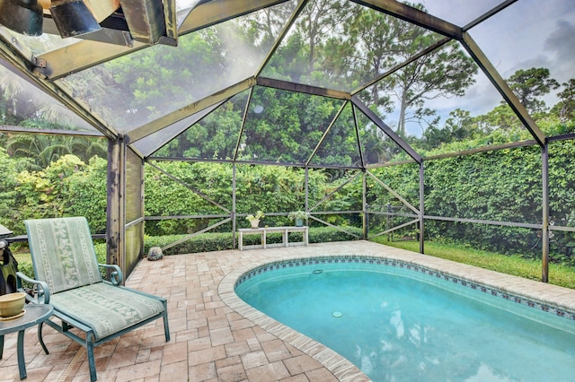 view of swimming pool with glass enclosure and a patio