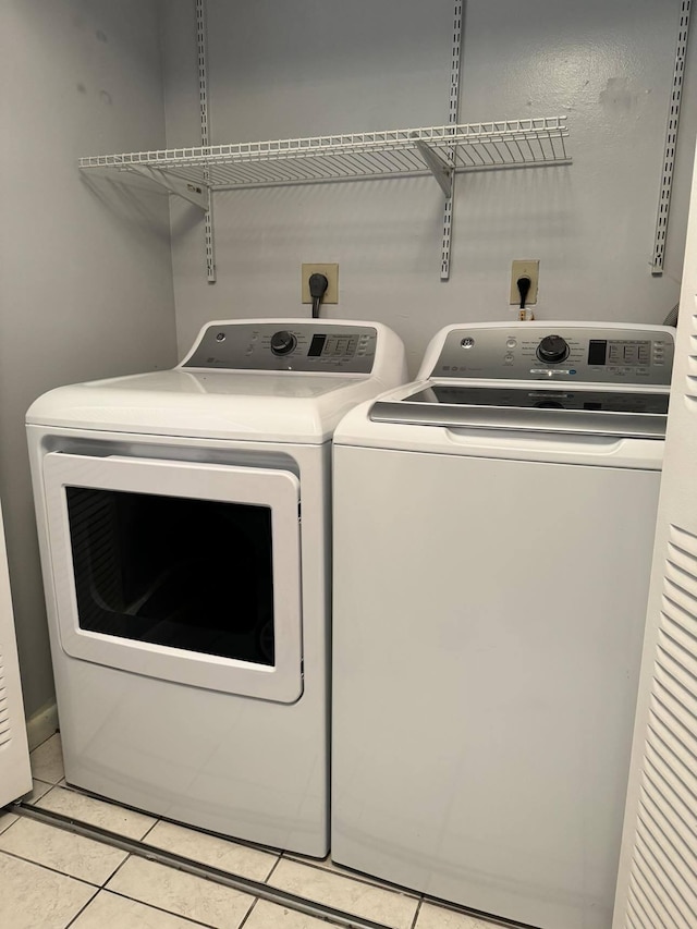 laundry area with electric dryer hookup, washing machine and dryer, and light tile flooring