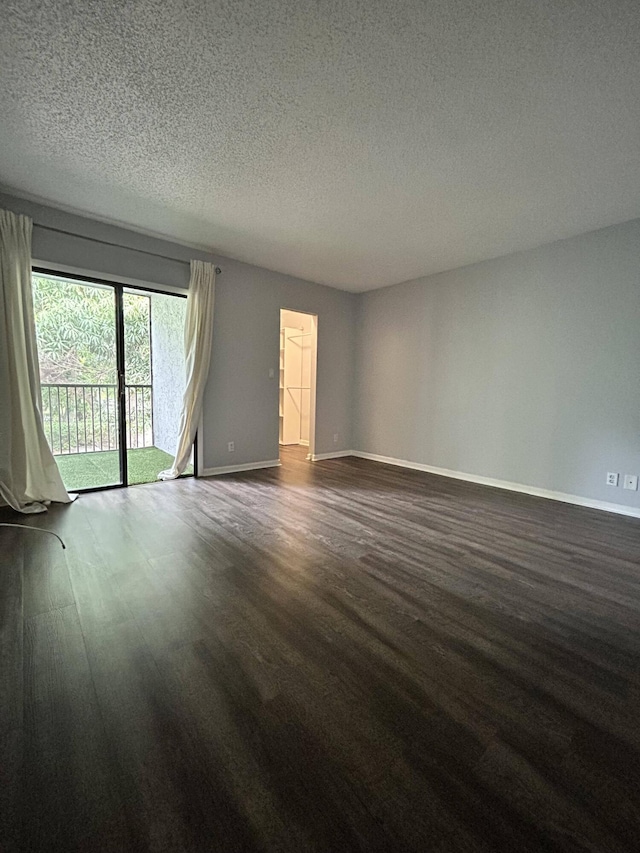 unfurnished room with a textured ceiling and dark hardwood / wood-style flooring