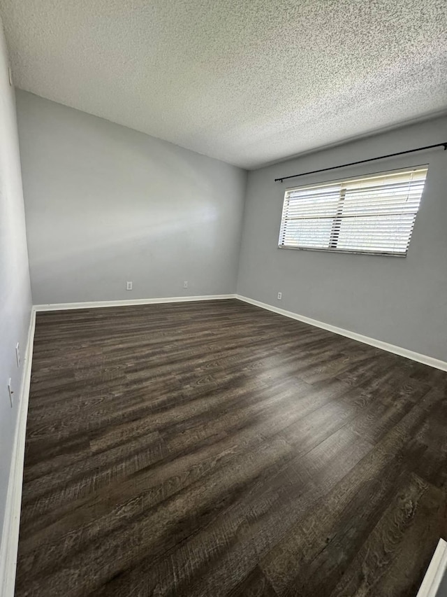 spare room with a textured ceiling and dark wood-type flooring