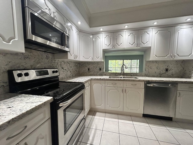 kitchen featuring appliances with stainless steel finishes, backsplash, crown molding, light tile flooring, and sink