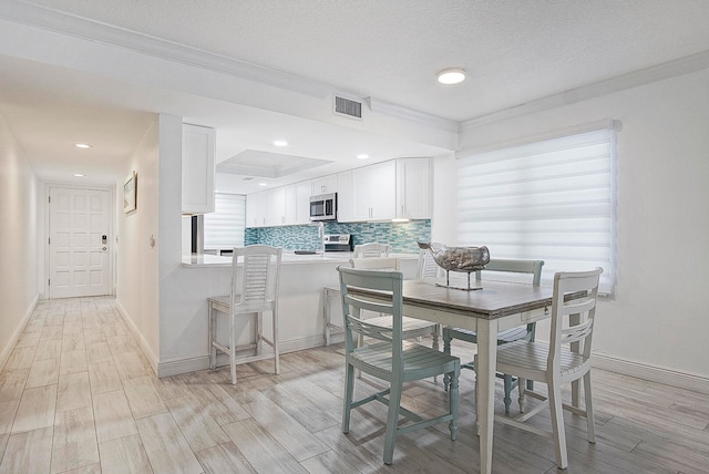 dining area with a textured ceiling, light wood-type flooring, and a wealth of natural light