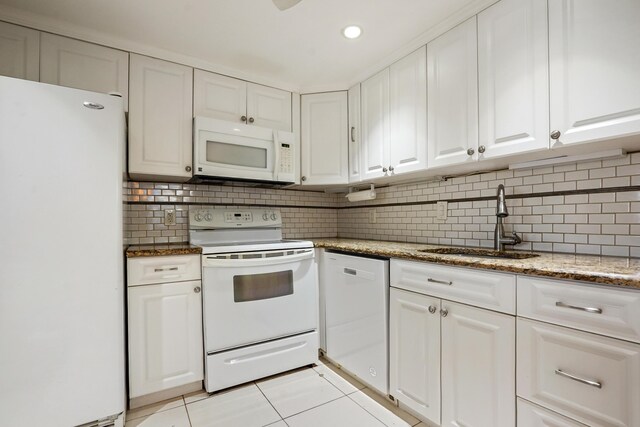 kitchen featuring light tile patterned flooring, white cabinetry, white appliances, light stone counters, and backsplash