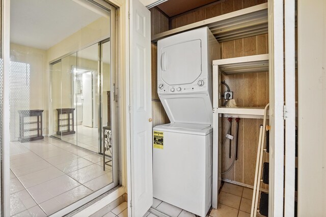 clothes washing area with light tile patterned flooring and stacked washer / dryer