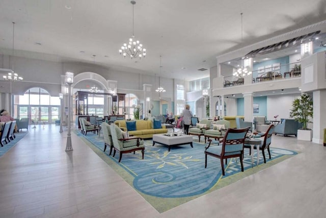 interior space with a towering ceiling, hardwood / wood-style floors, ornate columns, and an inviting chandelier