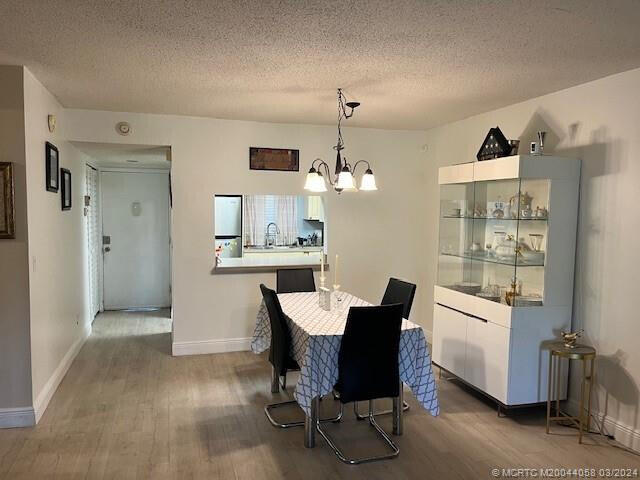 dining room featuring hardwood / wood-style floors, a chandelier, and a textured ceiling