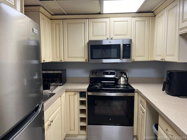 kitchen featuring cream cabinetry and appliances with stainless steel finishes