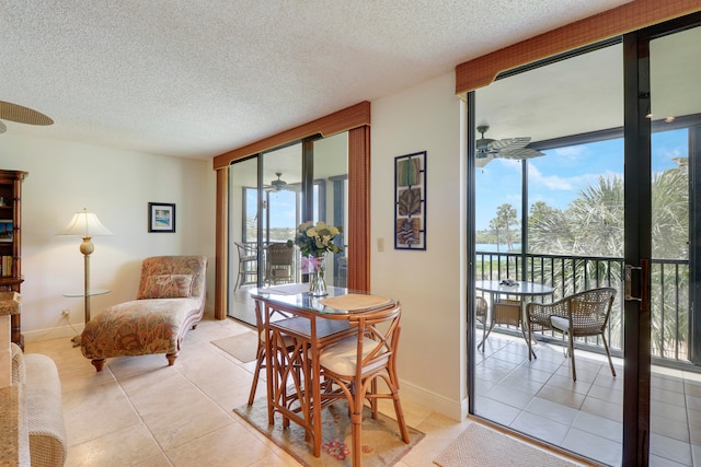 dining area featuring ceiling fan, a wall of windows, light tile patterned floors, and a textured ceiling