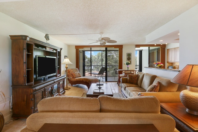 living room with ceiling fan, light tile patterned floors, and a textured ceiling