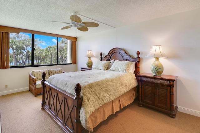 bedroom with a textured ceiling, light colored carpet, and ceiling fan