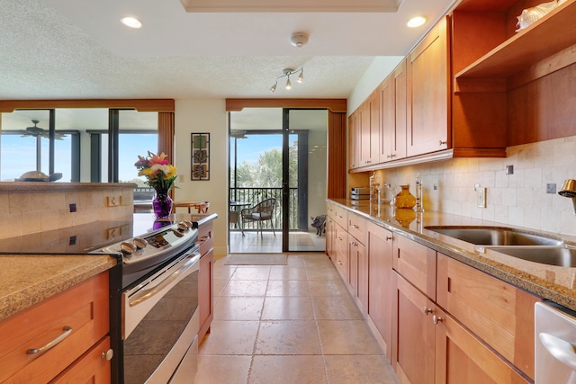 kitchen featuring decorative backsplash, appliances with stainless steel finishes, light stone countertops, a textured ceiling, and sink