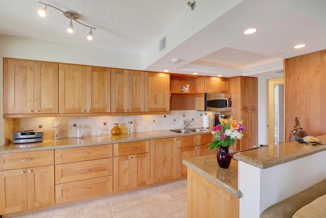 kitchen featuring decorative backsplash, sink, light stone counters, and a textured ceiling