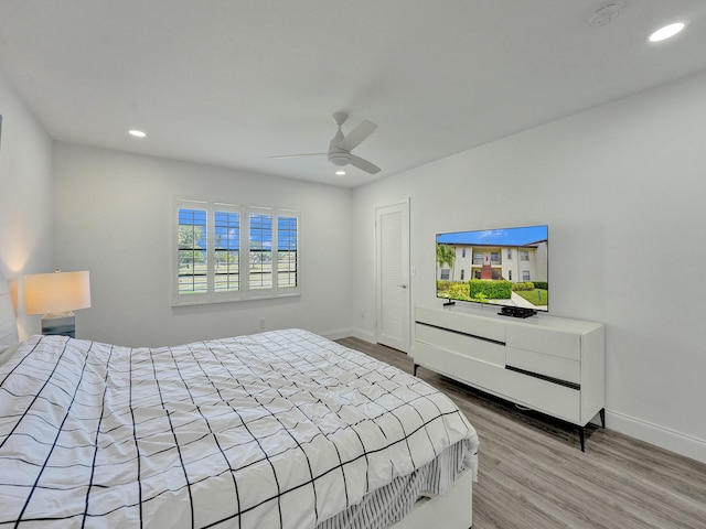 bedroom with light hardwood / wood-style flooring, ceiling fan, and a closet