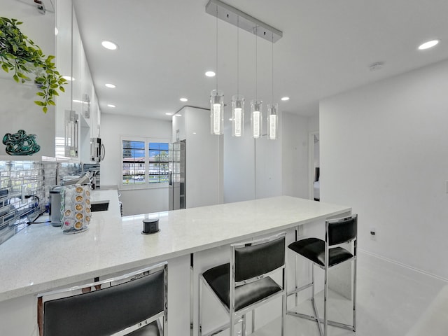 kitchen with a kitchen bar, white cabinetry, pendant lighting, and appliances with stainless steel finishes