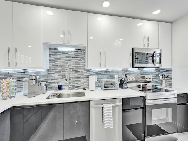 kitchen featuring stainless steel appliances, white cabinetry, sink, and backsplash