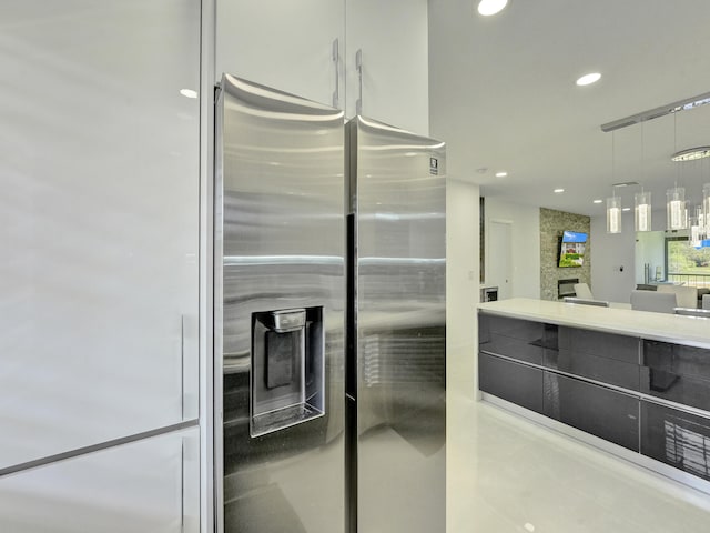 kitchen with pendant lighting, stainless steel refrigerator with ice dispenser, and a fireplace