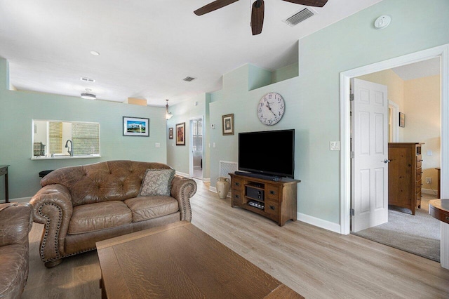 living room with light hardwood / wood-style flooring and ceiling fan