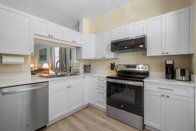 kitchen with sink, white cabinetry, light hardwood / wood-style flooring, appliances with stainless steel finishes, and light stone countertops