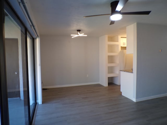 spare room with built in features, dark hardwood / wood-style flooring, and ceiling fan