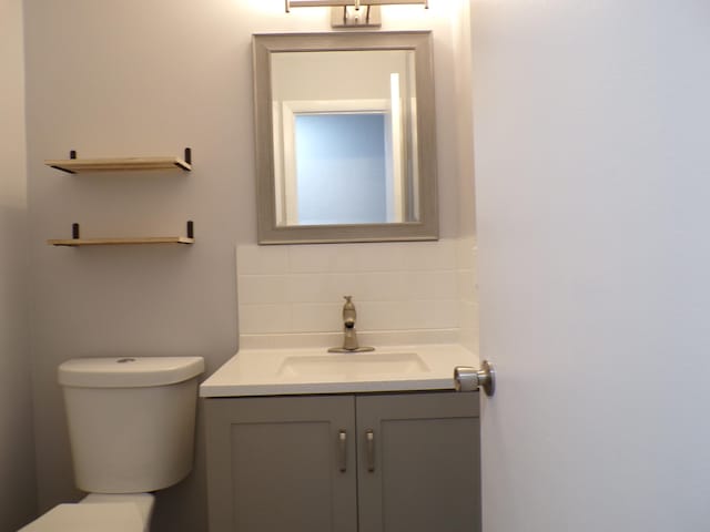 bathroom with backsplash, vanity, and toilet