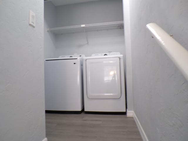 clothes washing area with washing machine and dryer and wood-type flooring