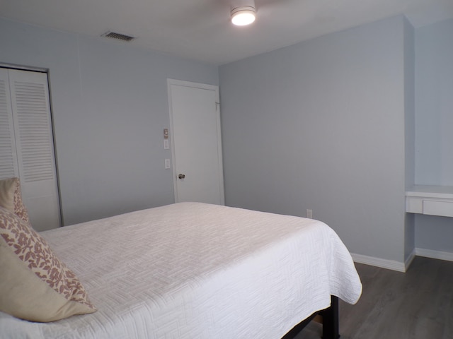 bedroom with dark hardwood / wood-style flooring and a closet