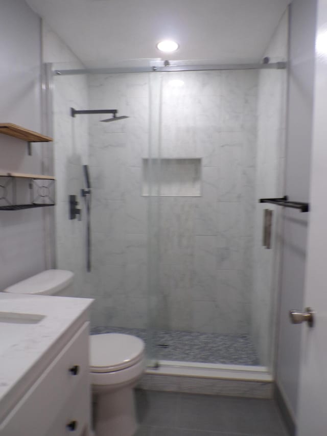 bathroom featuring tiled shower, vanity, toilet, and tile floors