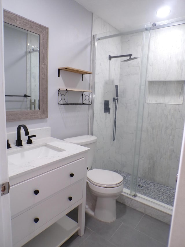 bathroom featuring vanity, toilet, tile floors, and a shower with door