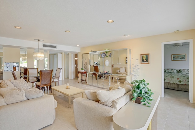 tiled living room with a textured ceiling and ceiling fan with notable chandelier