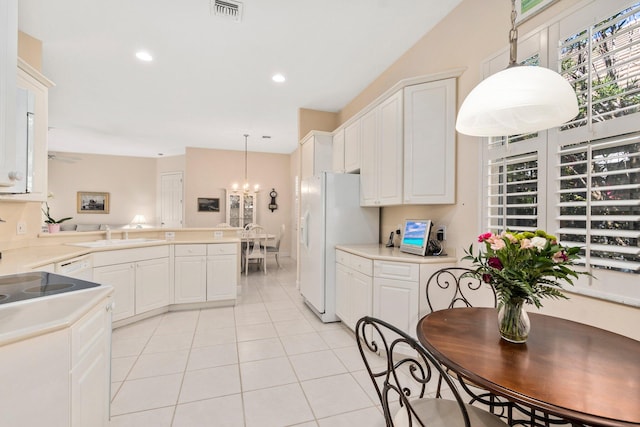 kitchen featuring white cabinets, kitchen peninsula, light tile floors, and hanging light fixtures