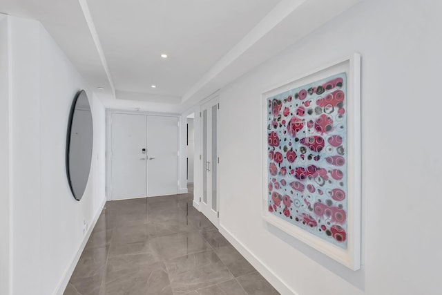 hall with tile floors and a tray ceiling