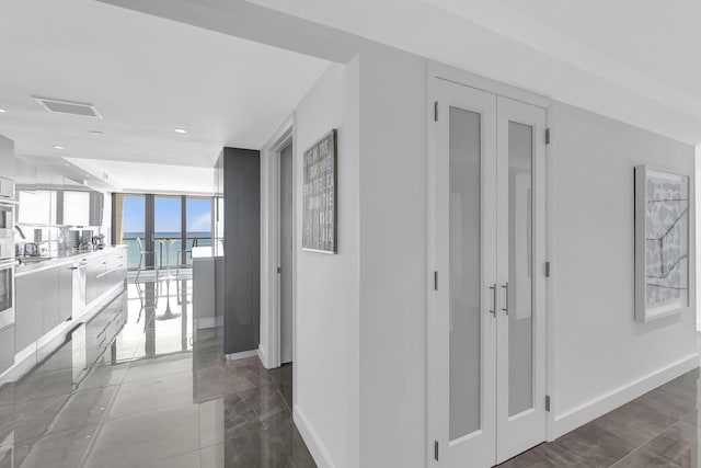 hall with dark tile flooring and a wall of windows